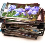 Pile of assorted printed photographs with visible iris flower.